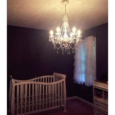 a chandelier hanging from the ceiling in a baby's room with purple walls