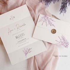 the wedding stationery is laid out on top of the pink blanket and purple flowers