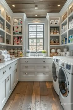 a washer and dryer in a room with white cabinets, wood flooring and open shelving