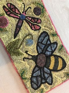 a close up of a piece of cloth with embroidered designs on it and two bees