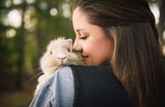 a woman is holding a small rabbit in her arms and kissing it's face