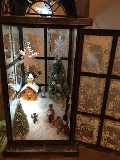 a small christmas scene in a window with snow on the windowsill and trees outside