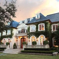 a large white house with lots of windows and ivy growing on it's walls