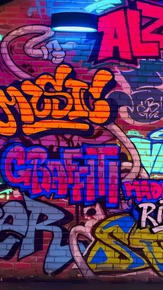 graffiti on the side of a brick building in an alleyway with various colors and sizes