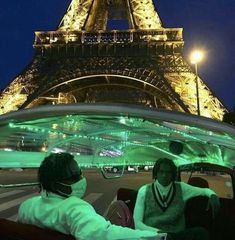 two people are sitting in a tour bus near the eiffel tower at night