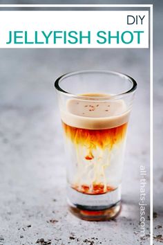 a shot glass filled with liquid sitting on top of a cement floor next to a sign that says jellyfish shot