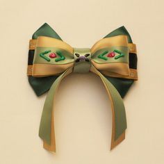 a close up of a bow on a white wall with green and gold ribbon around it