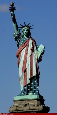 the statue of liberty is holding a torch in its right hand and reading a book