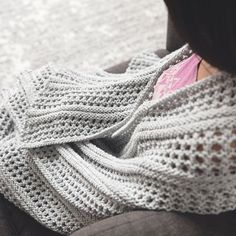 a woman sitting on a couch wearing a knitted sweater