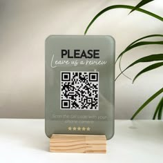 a wooden stand with a qr code on it next to a potted plant