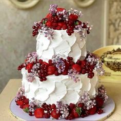 a three tiered cake with berries and flowers on it