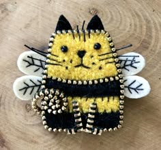 a yellow and black cat brooch sitting on top of a wooden table