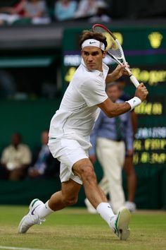 a man swinging a tennis racquet on top of a tennis court with people watching