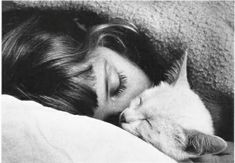 a black and white photo of a woman sleeping with her cat