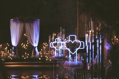 a cross is lit up in the middle of a room filled with candles and other decorations