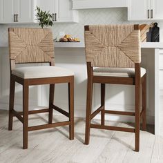 two wooden stools sitting next to each other in front of a white kitchen counter