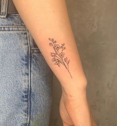 a woman's arm with a small flower tattoo on the left side of her arm