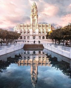 a large building with a clock tower in the middle of it's reflection pool