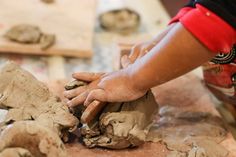 a person making clay on a table with their hands in the middle and one hand holding something