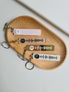 three keychains with different types of sound waves on them sitting on a wooden tray