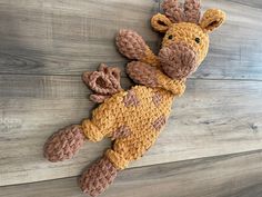 a crocheted stuffed giraffe laying on top of a wooden floor next to a wall