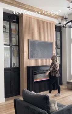 a woman standing in front of a fireplace with a tv on it's side