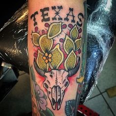 a tattoo on the arm of a man with flowers and an animal's skull