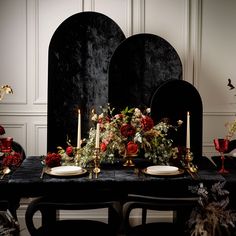 a black table topped with plates and candles