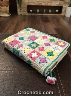 a crocheted granny blanket sitting on top of a brown leather couch next to a fireplace