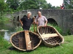 two men standing next to canoes on the grass