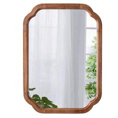 a wooden mirror sitting on top of a table next to a potted green plant