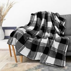 a black and white plaid blanket sitting on top of a couch next to a vase