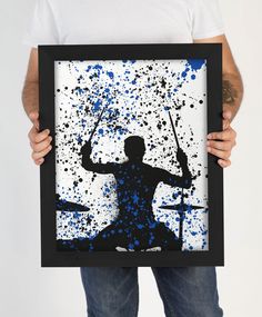 a man holding up a framed photo with paint splattered on it