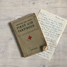 the first aid book is next to an old handwritten note