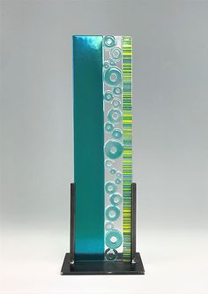 a tall blue and green glass award on a black stand