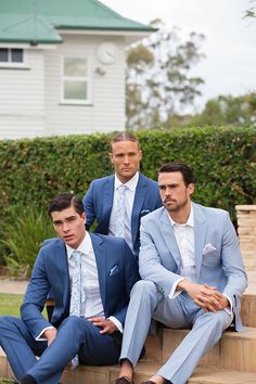 three men in suits are sitting on steps near each other and posing for the camera