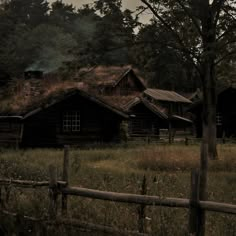 an old log cabin with grass on the roof