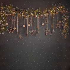 christmas decorations are hanging on the wall with lights and garlands around them, along with pineconis