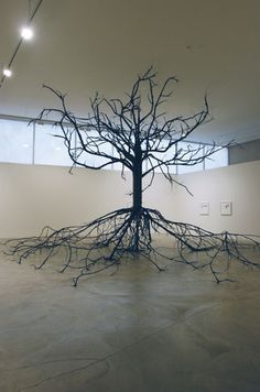 an art installation in the middle of a room with exposed branches on the floor and walls