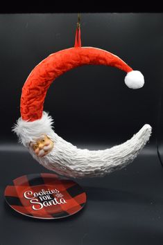 an ornament with a santa hat hanging from it's side on a black surface