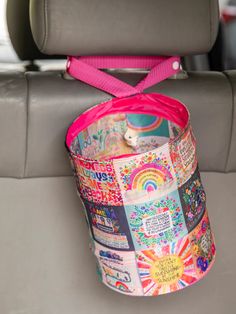 a colorful bucket is sitting in the back seat of a car with a pink ribbon tied around it