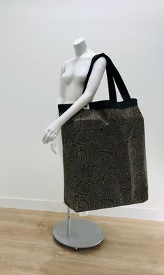 a mannequin's torso wearing a black and brown tote bag on display