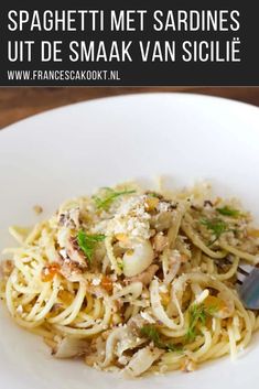 a white plate topped with pasta and sauce next to a fork on top of a wooden table