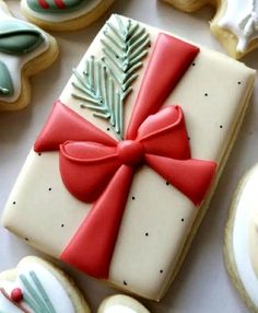 decorated cookies with red ribbon and bow on white table top next to cookie cutters