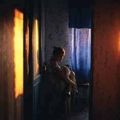 a woman sitting in a chair next to a window with the sun shining through it