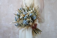 a woman holding a bouquet of flowers in her hands and wearing a white dress with feathers on it