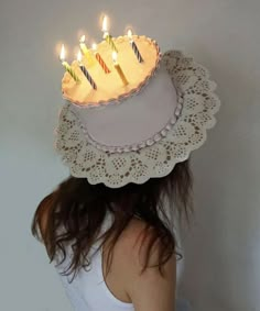 a woman wearing a birthday cake hat with lit candles