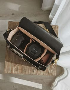 an open camera bag sitting on top of a wooden table