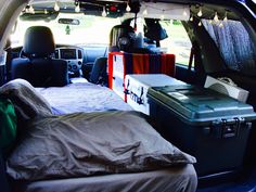 an open trunk in the back of a vehicle with luggage and blankets on it's bed