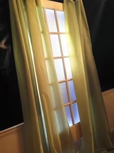 an open window with yellow curtains in front of it